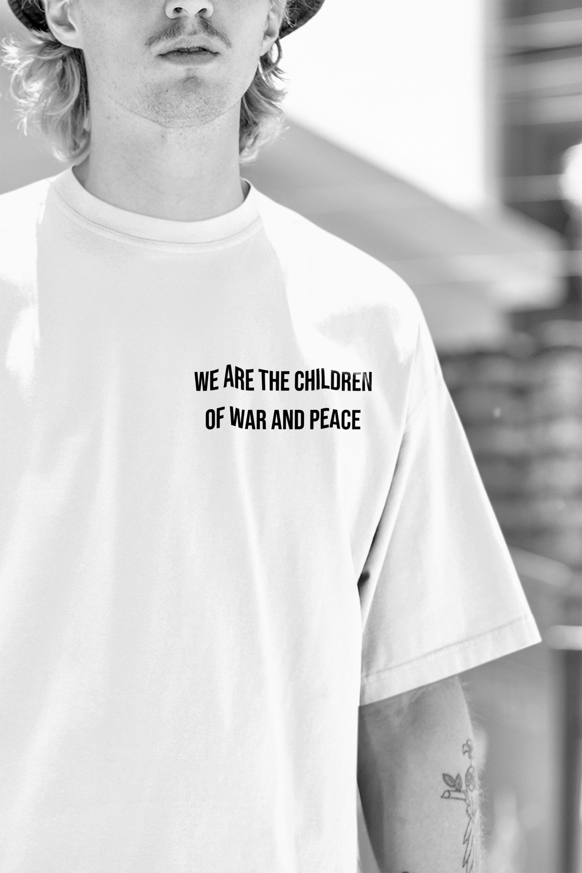 A black-and-white photo of a person wearing a T-shirt with the text "We are the children of war and peace" on it.