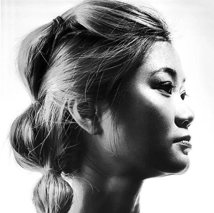 Black and white close-up profile of a woman with styled hair and makeup.