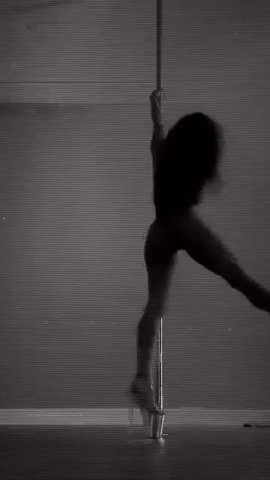 Silhouette of a pole dancer performing on a pole in front of a horizontal-striped background.