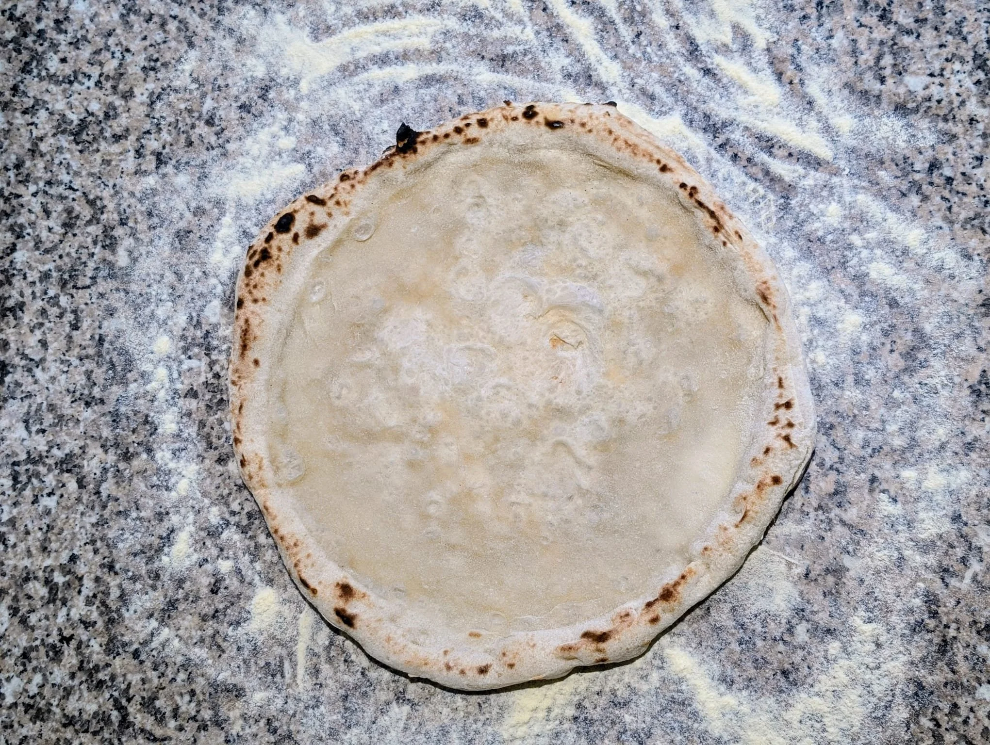 A round piece of rolled-out dough on a floured countertop.