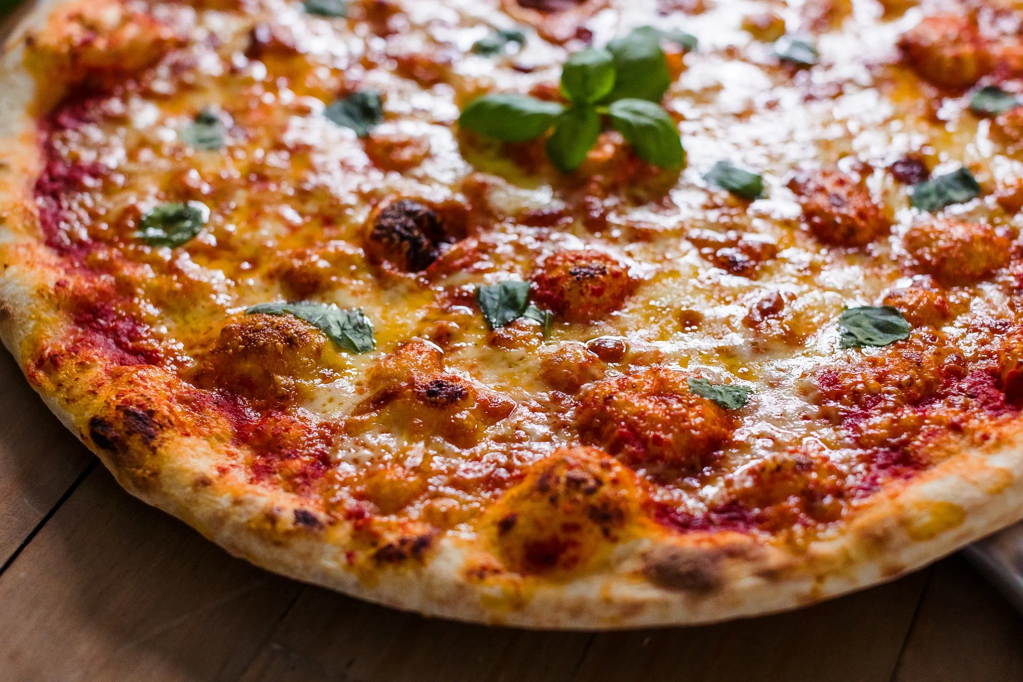 Close-up of a New York pizza topped with basil leaves.