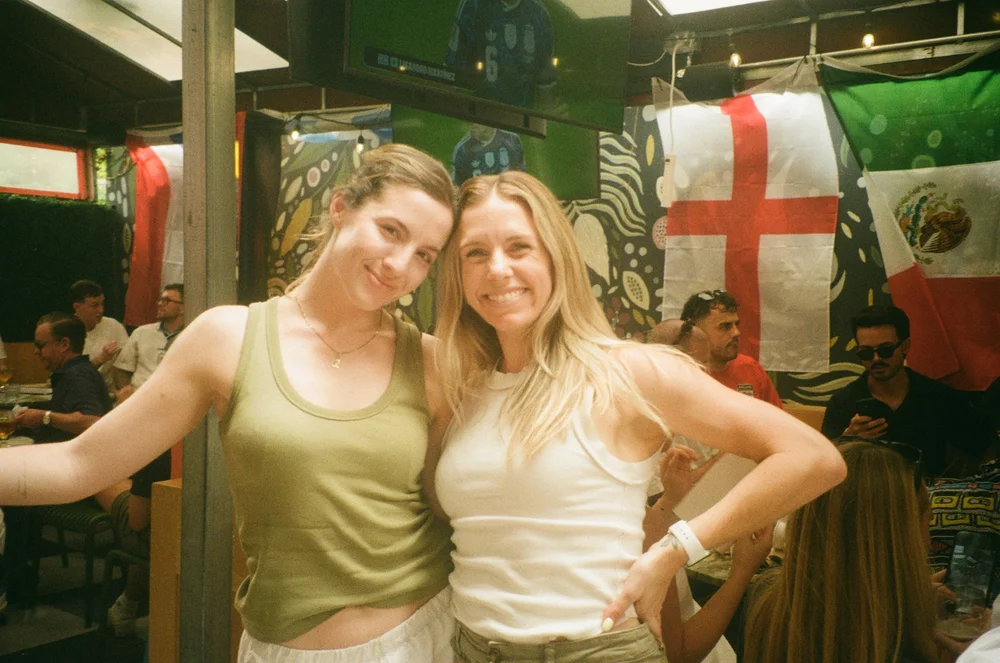 Two teammates posing under flags, shot on film