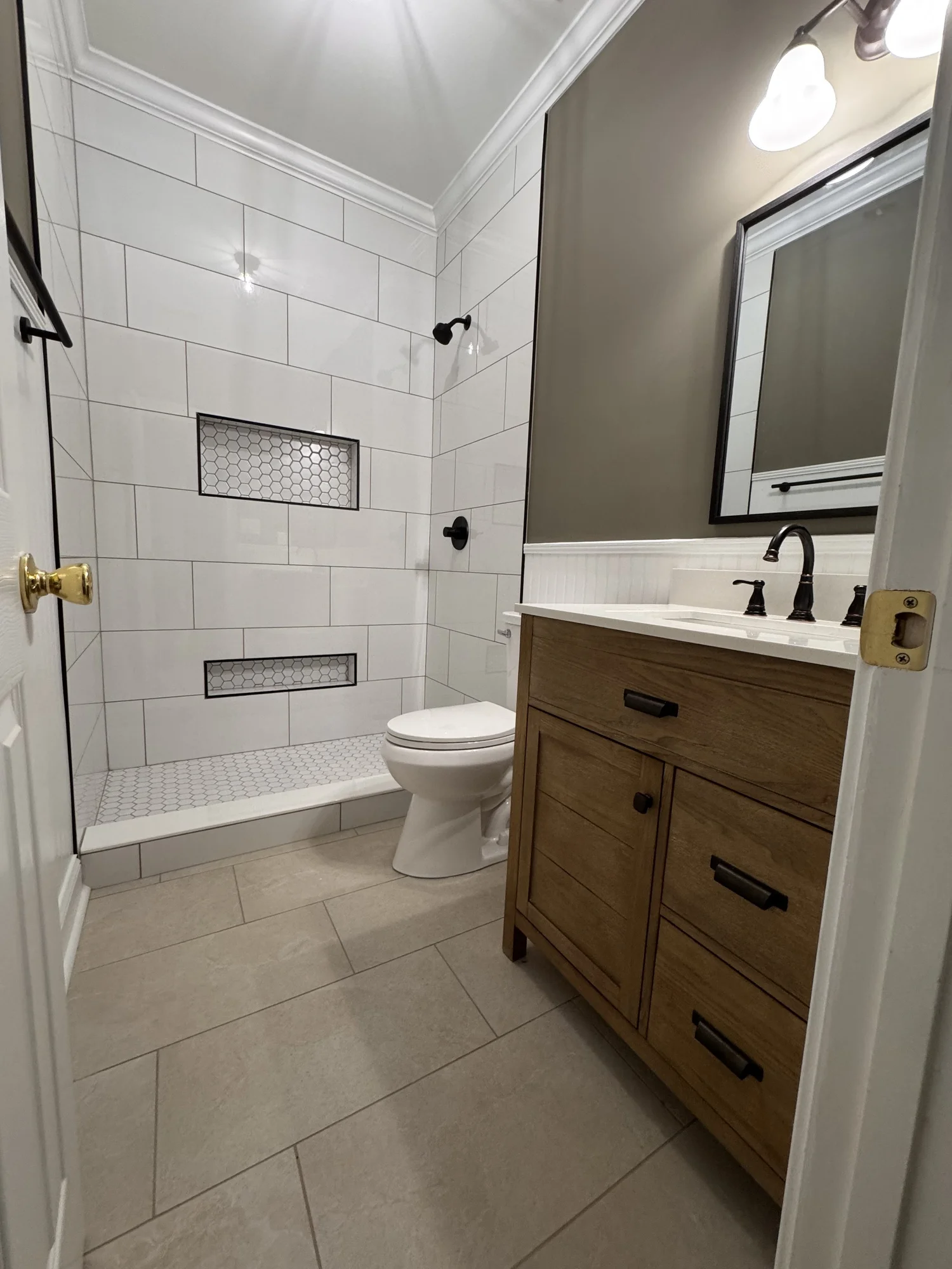 Wood bathroom vanity and tiled shower with inset niches