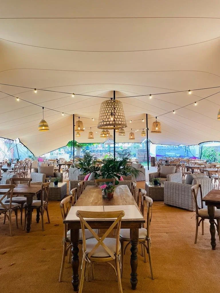 Pendant lighting along with Moroccan lampshades strung between centre poles to create a warm glow within the tent