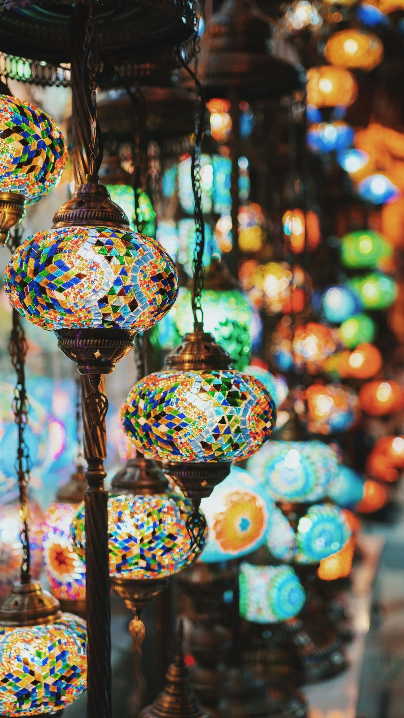 Colorful mosaic Turkish lanterns hanging in a marketplace.