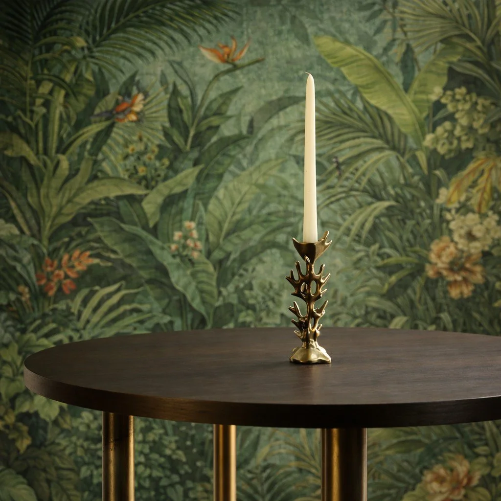 Kerzenständer mit einer weißen Kerze auf dunklem Holz Tisch, davor ein grüner, blühender Dschungel-Hintergrund.