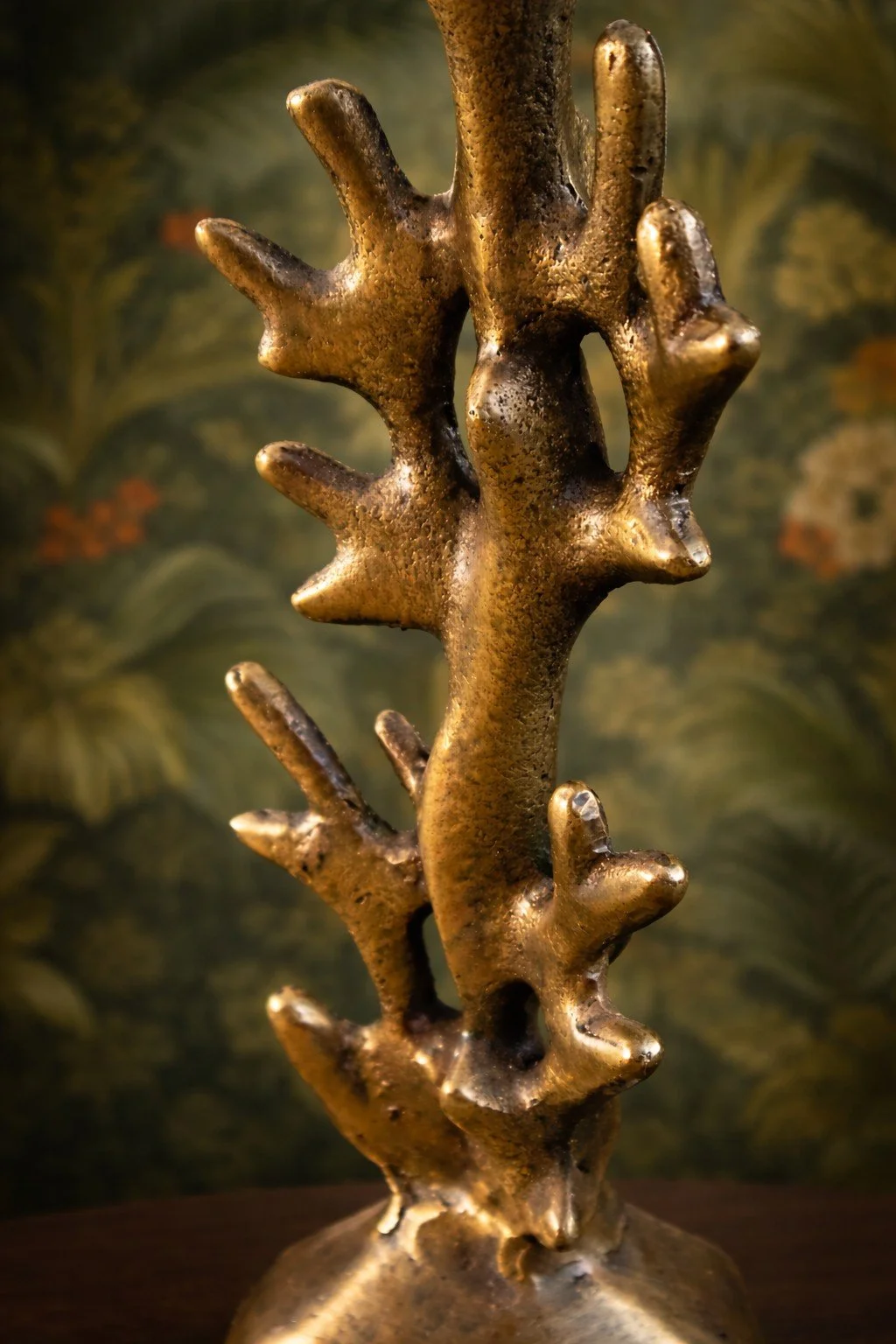 Eine kunstvolle Skulptur aus bronzeartigem Material, die wie eine abstrakte, organische Form aussieht, mit mehreren fingerartigen Erweiterungen.