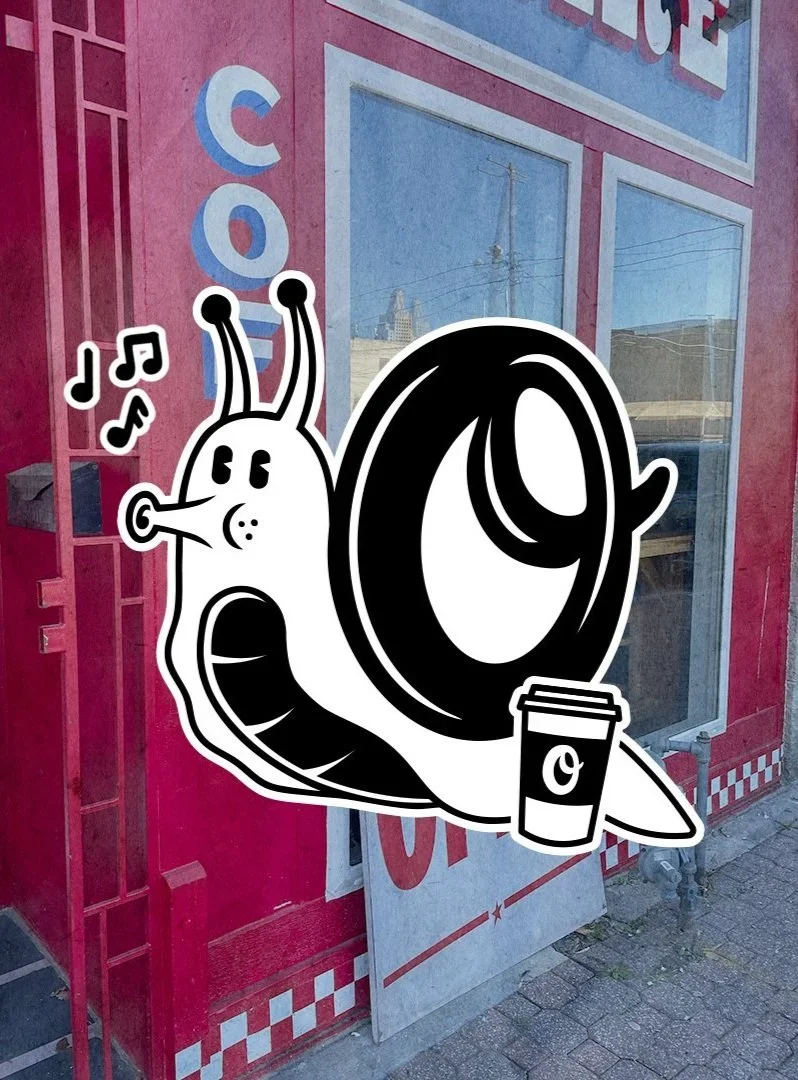 A cartoon sticker of a snail with a coffee cup, musical notes, and a sad face, placed on a pink storefront window.