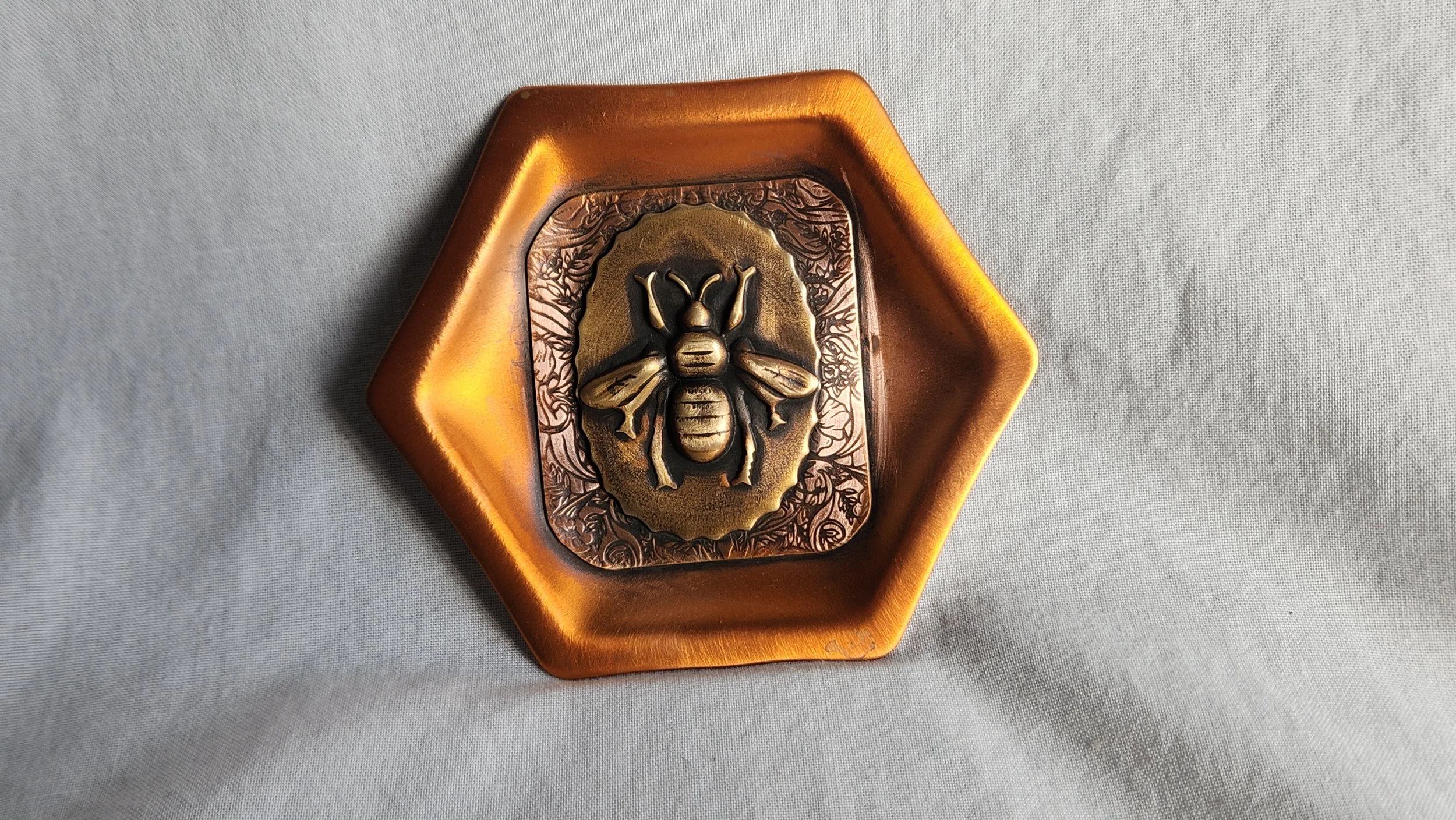 Hexagon shaped oxidized copper dish with die struck bee image.