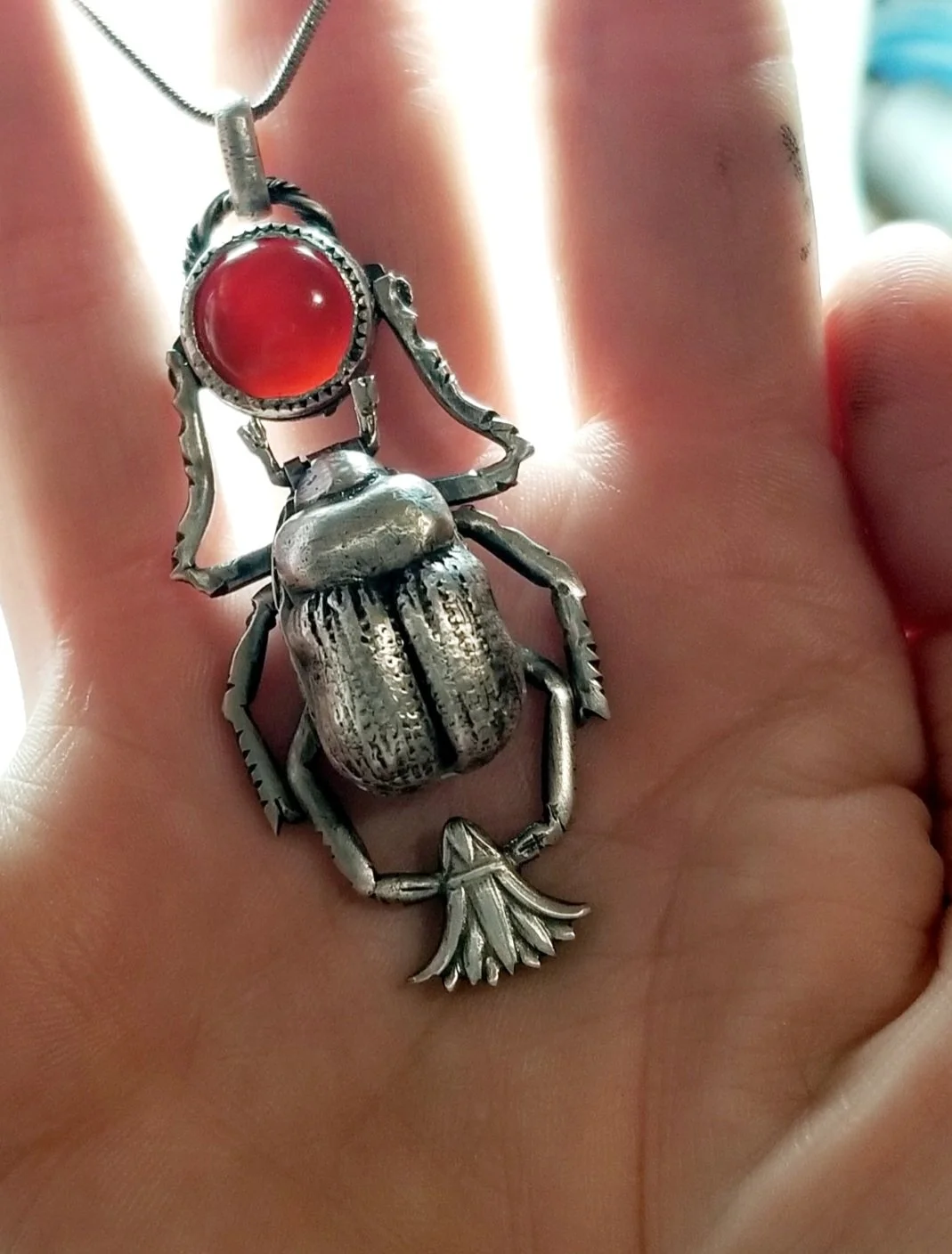 Wax carved and hand cast sterling silver scarab beetle locket with die struck papyrus flower and red carnelian stone.