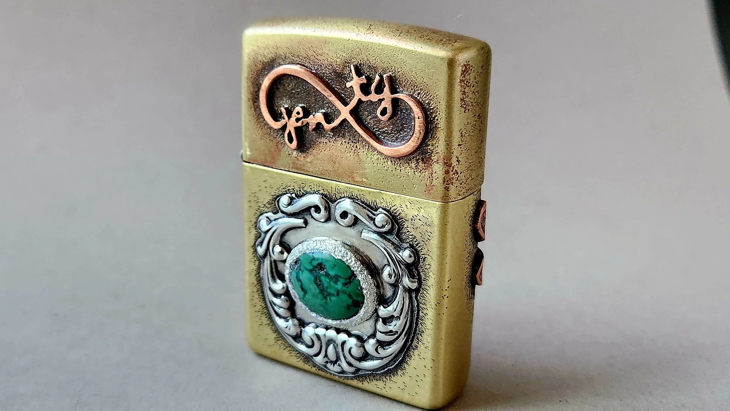 Brass lighter with die-struck  and hand sawn silver and copper elements and a set turquoise stone.