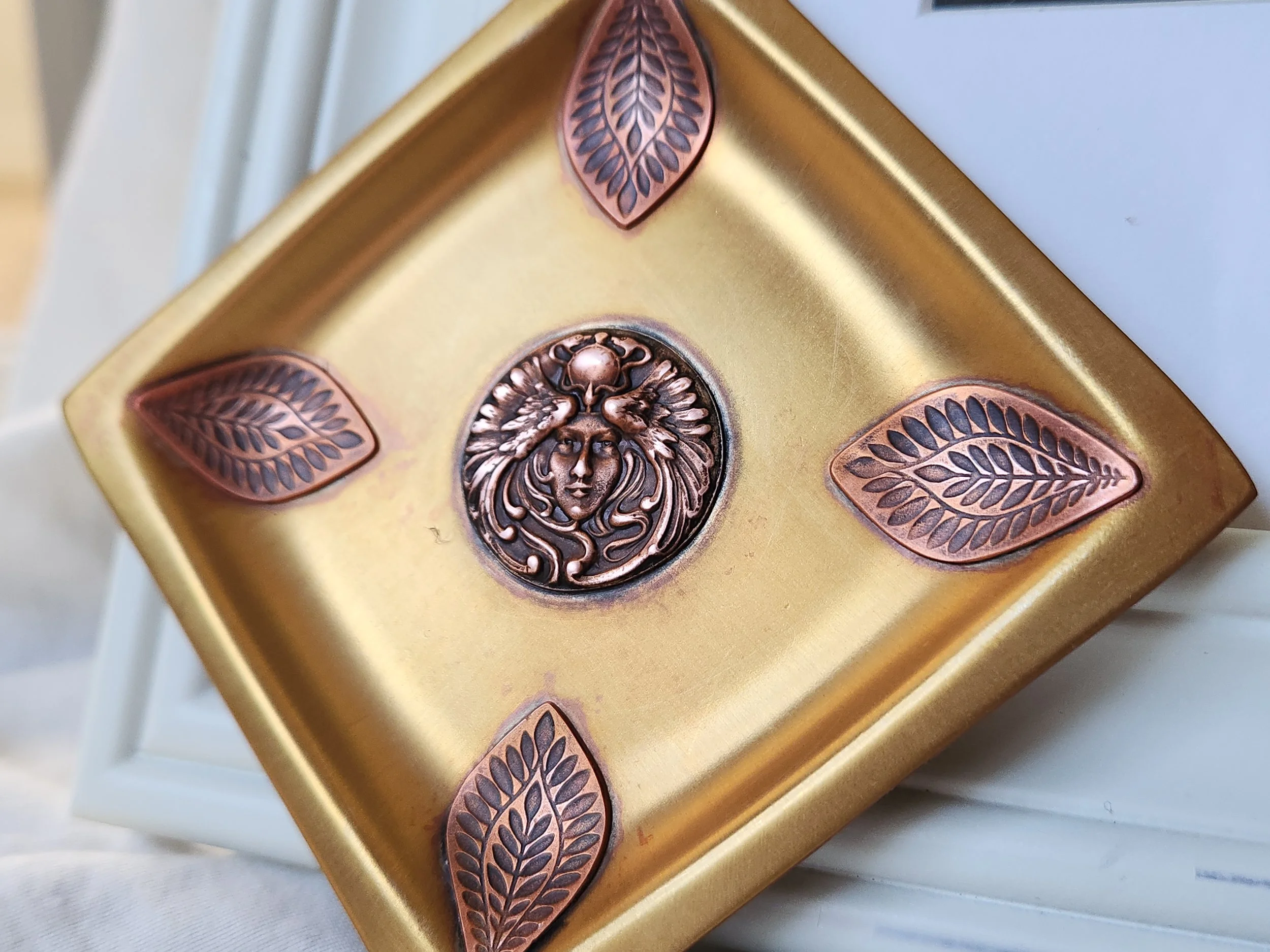 Square brass dish with die struck copper motif of a feather headdress woman.