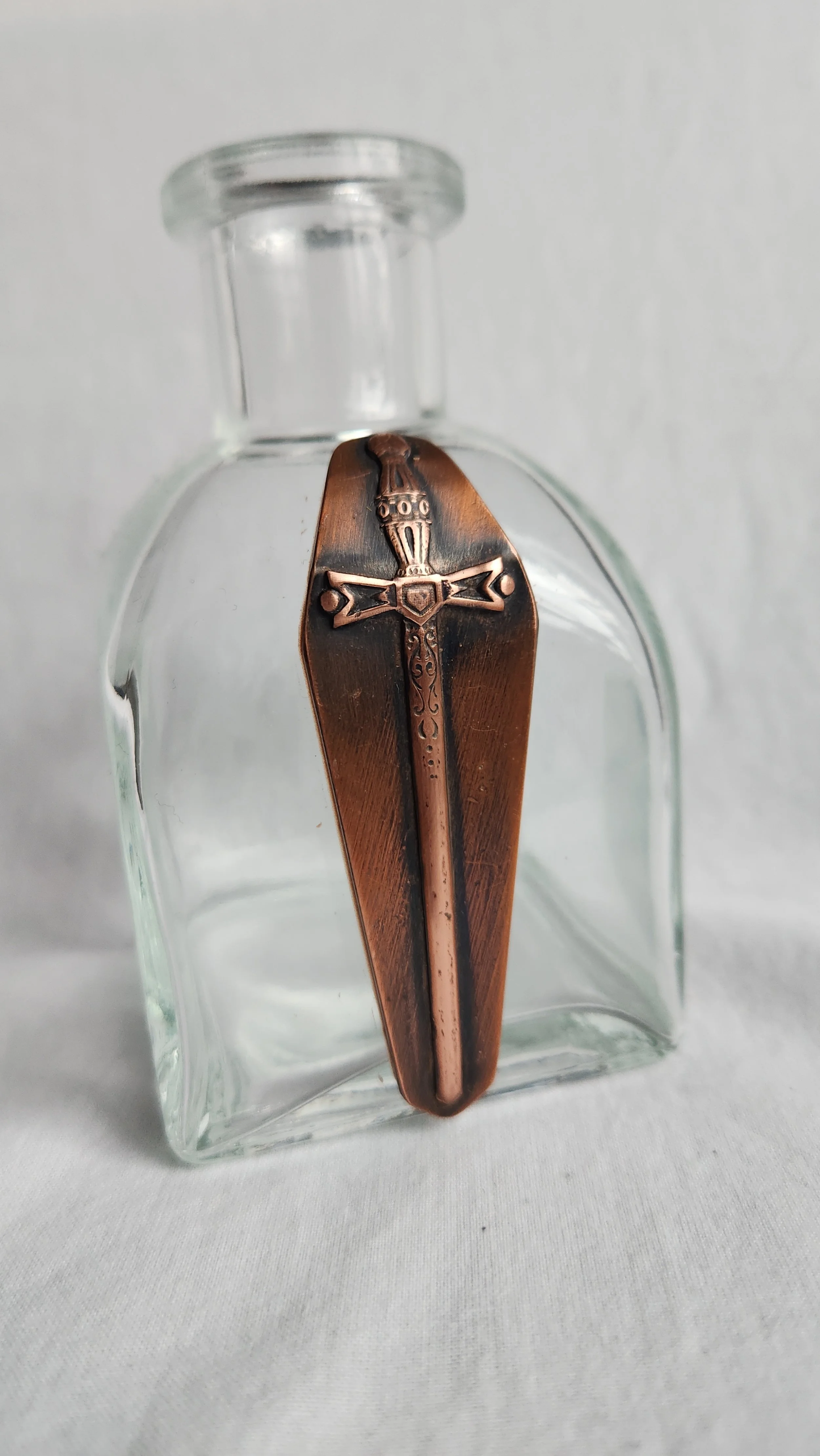 Die struck copper sword on a square glass propagation vase.