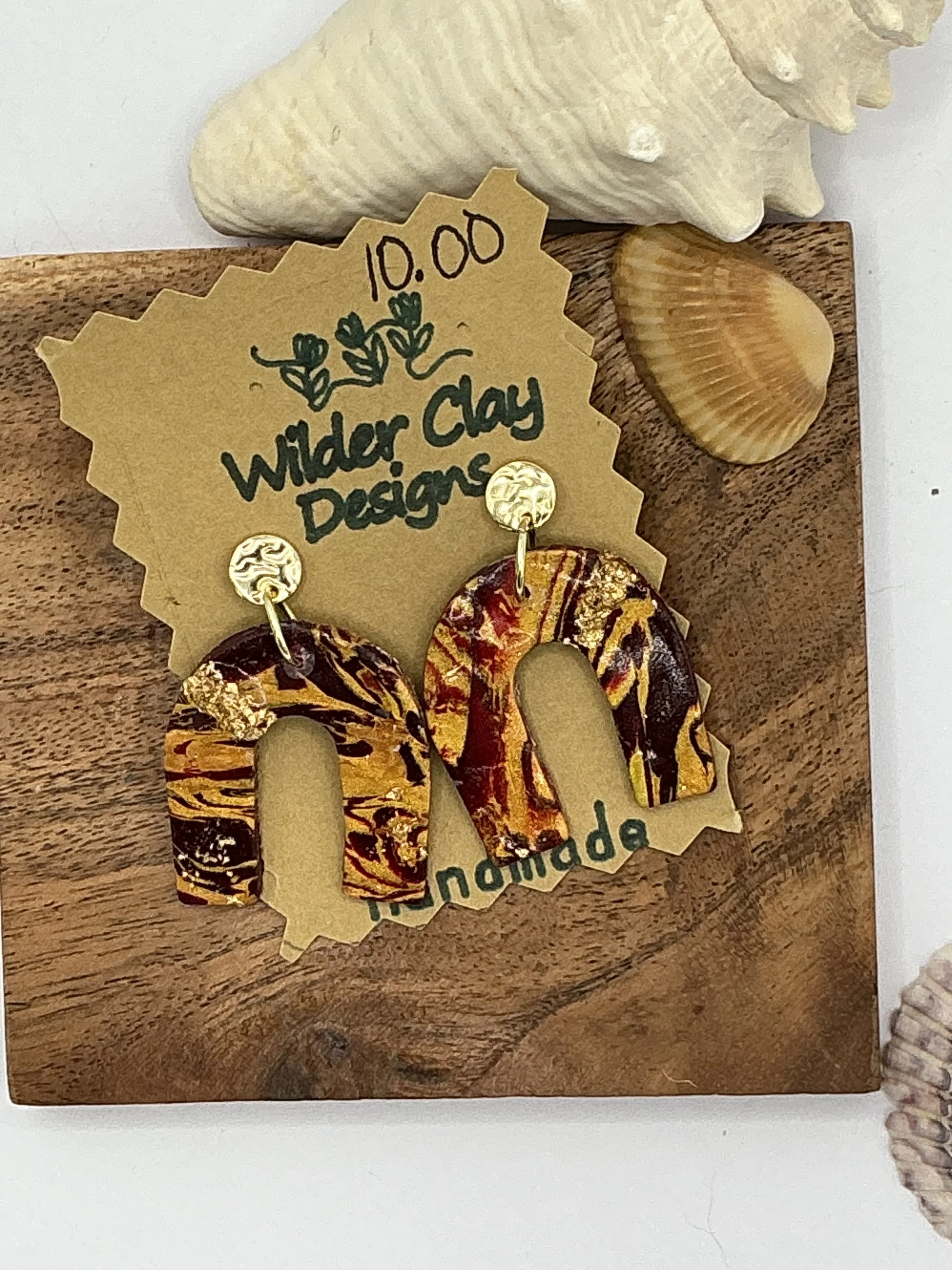 A pair of earrings with a marbled orange, yellow, and brown pattern. Perfect for an evening out.