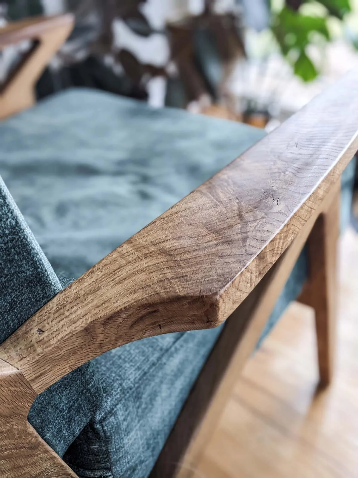 Close-up of a wooden armrest of a sofa or chair with denim upholstery.