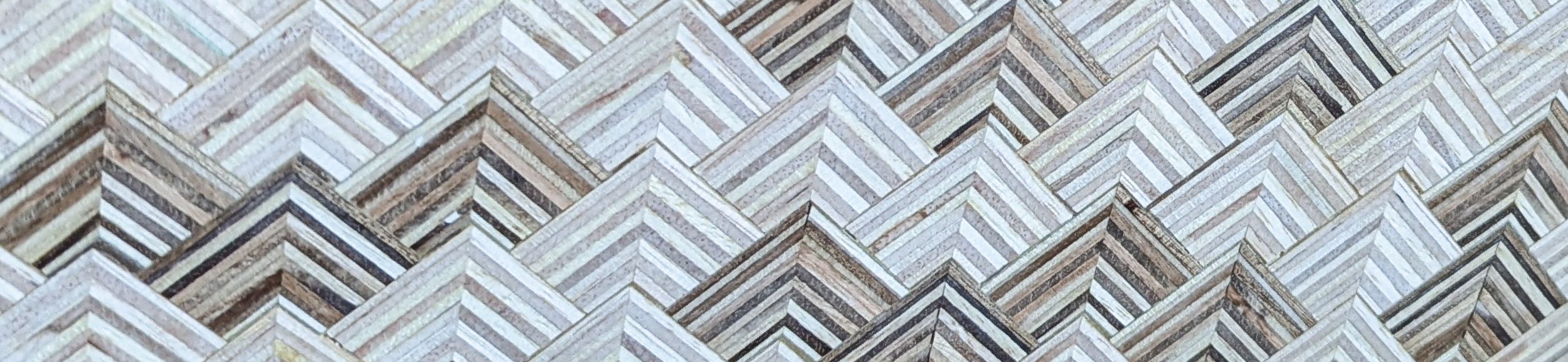 Close-up view of a geometric pattern made of wooden planks arranged in a chevron or herringbone design.