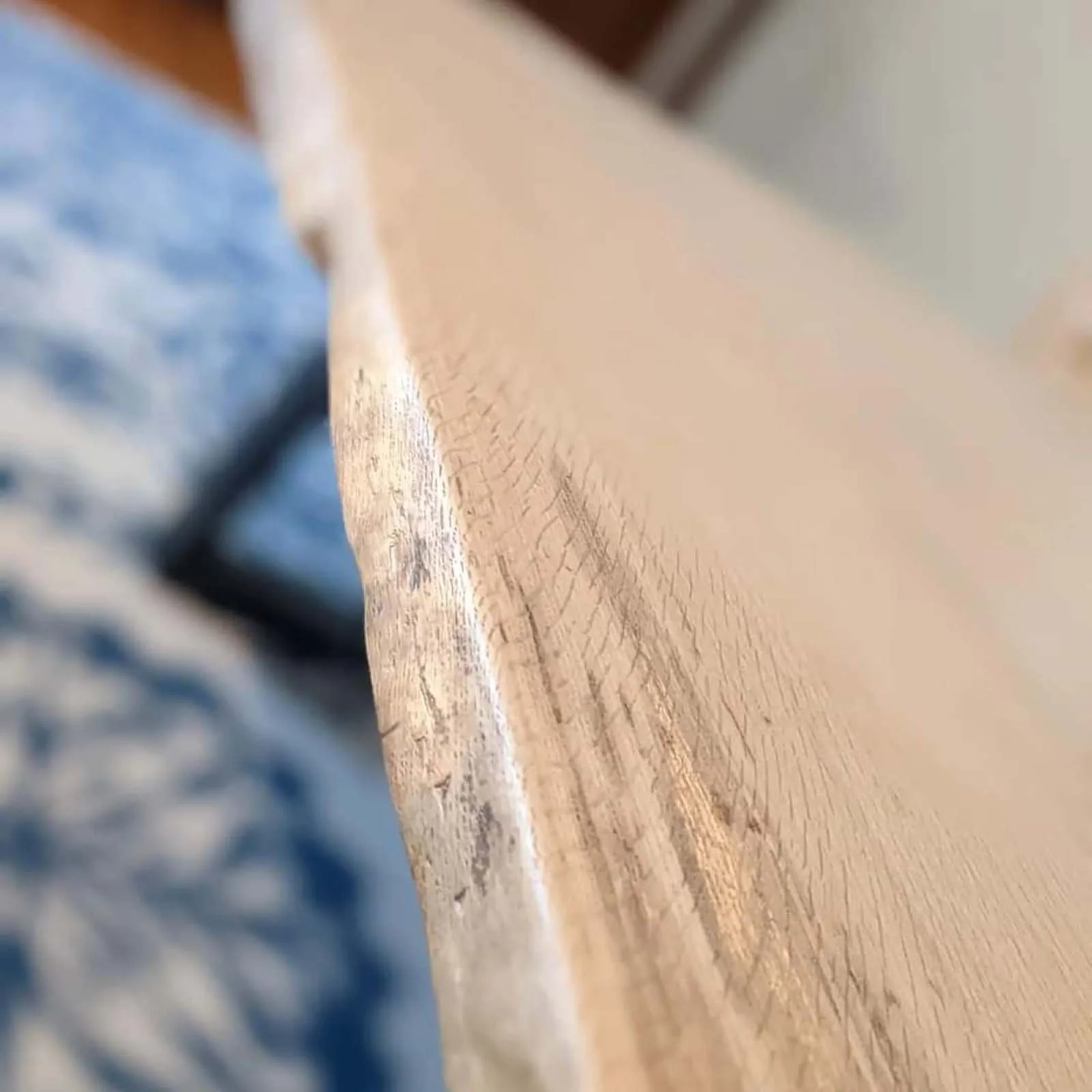 Close-up of a wooden surface with visible grain and a slightly worn edge.