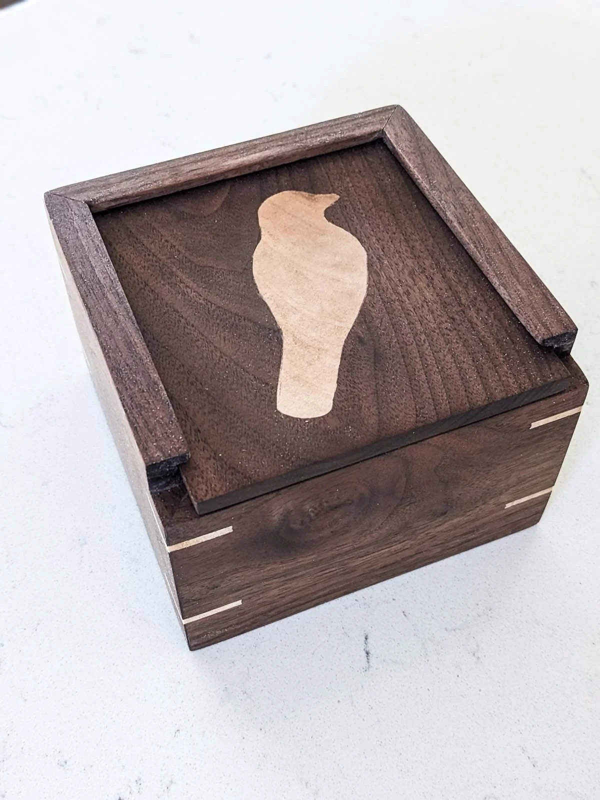 Wooden box with a light-colored bird silhouette on the top surface.