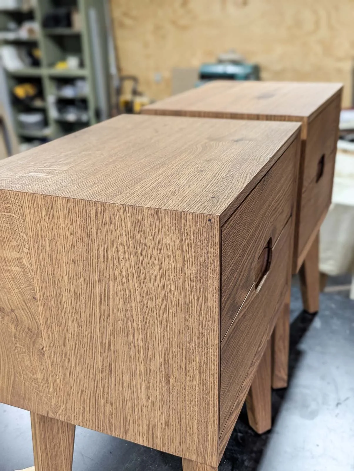 A wooden cabinet with a natural finish, showing clean lines and simple design, set in a workshop environment.