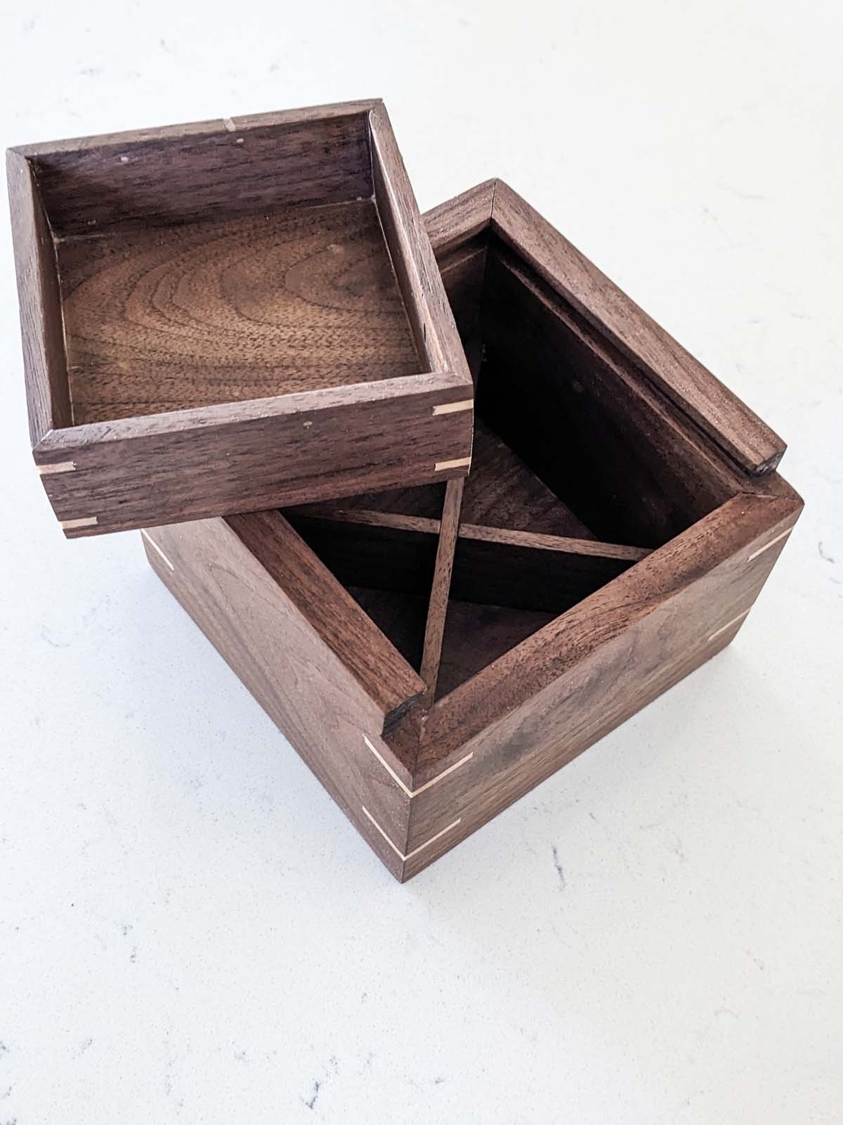 Two wooden boxes, one with a lid and one open, placed on a white surface.