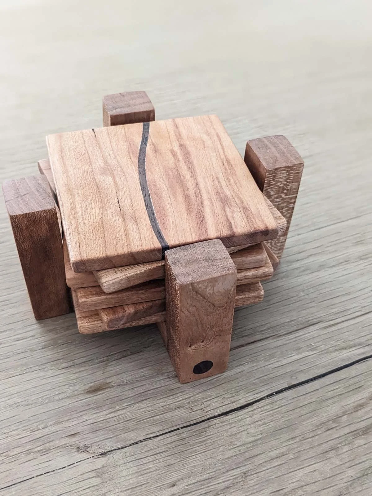 Stacked small wooden blocks with a black line painted on top block, placed on a light-colored wooden surface.