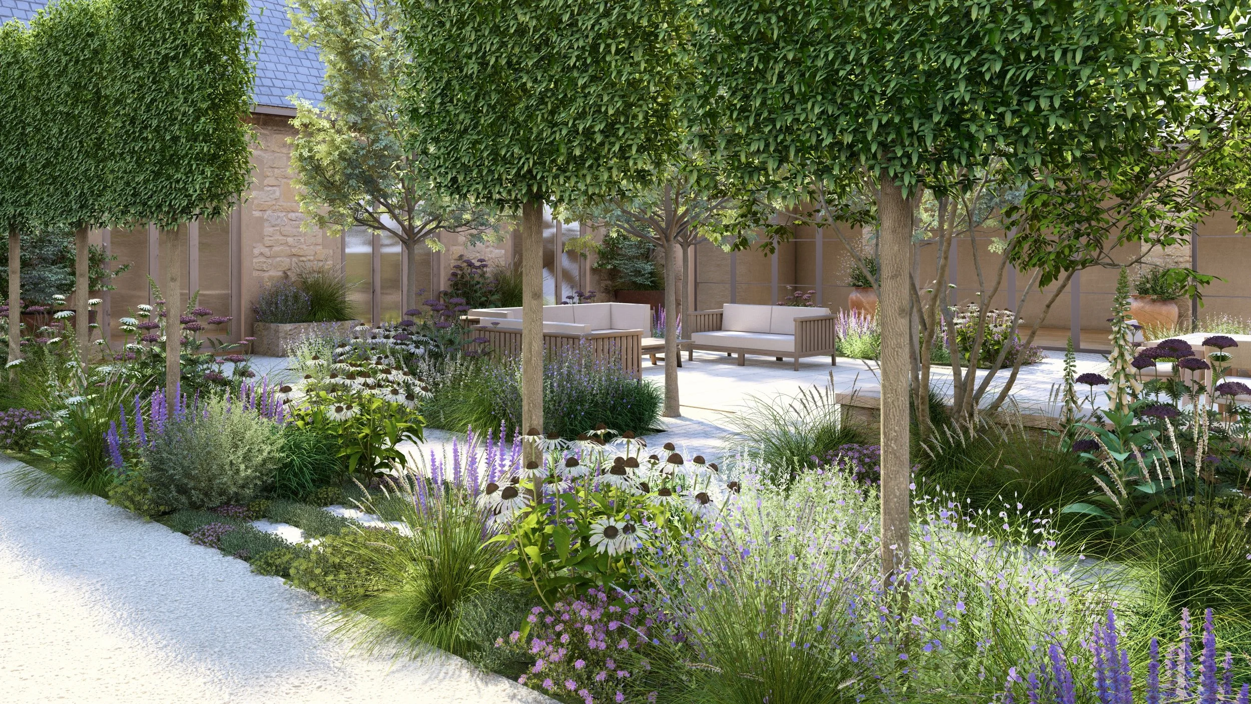 A beautiful garden design in a Cotswold barn conversion courtyard garden with pleached trees, generous seating area with sofas,  limestone paving and stepping stones, natural stone water trough planters and beautiful loose naturalistic planting