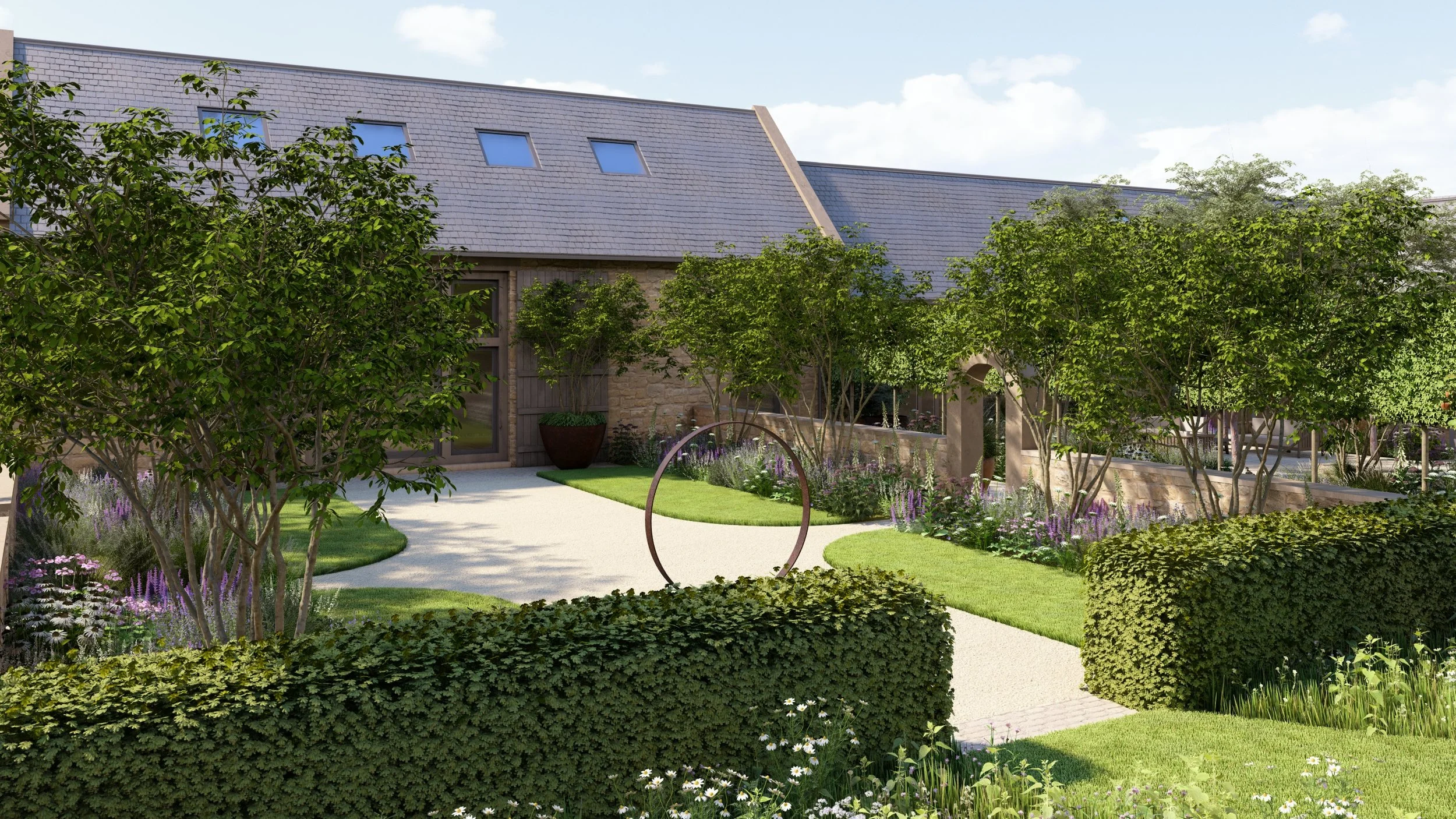 A Cotswolds barn conversion with a landscaped garden featuring a curved pathway and lawn, multi-stemmed trees, limestone walls, beech hedging, a central steel ring garden feature/sculpture, lots of colourful planting and a stone archway