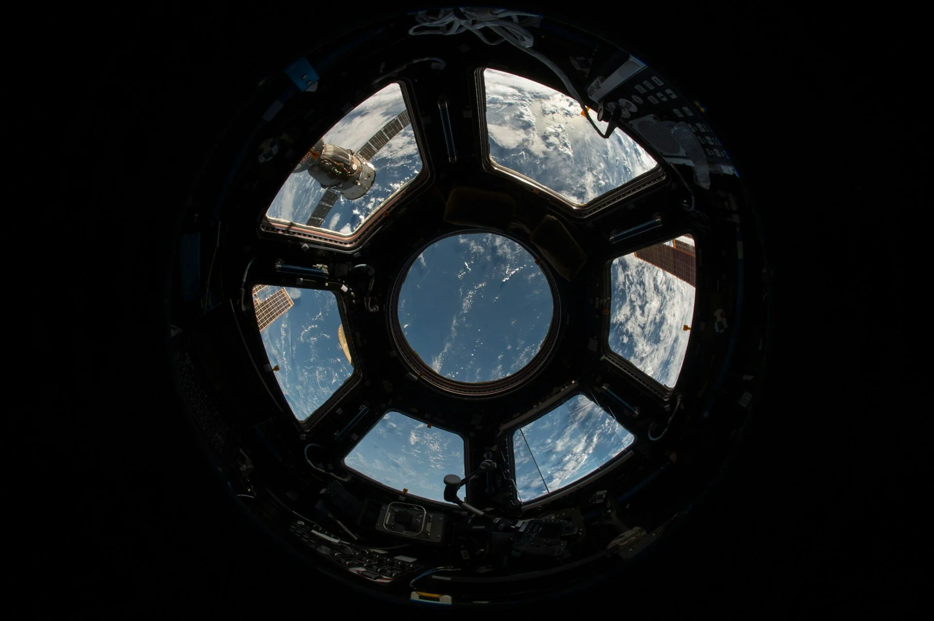 View of Earth through the windows of the International Space Station, showing the curvature of the planet and the surrounding space.