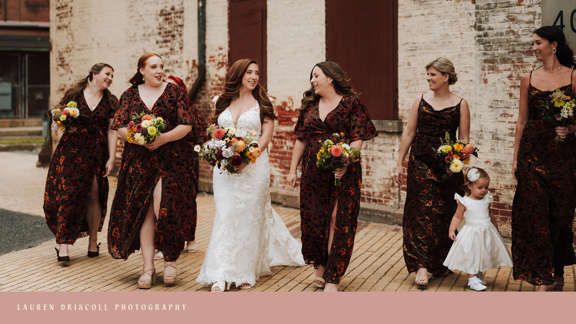 Bride and bridesmaids walking outdoors with bouquets, all smiling and dressed in wedding attire.