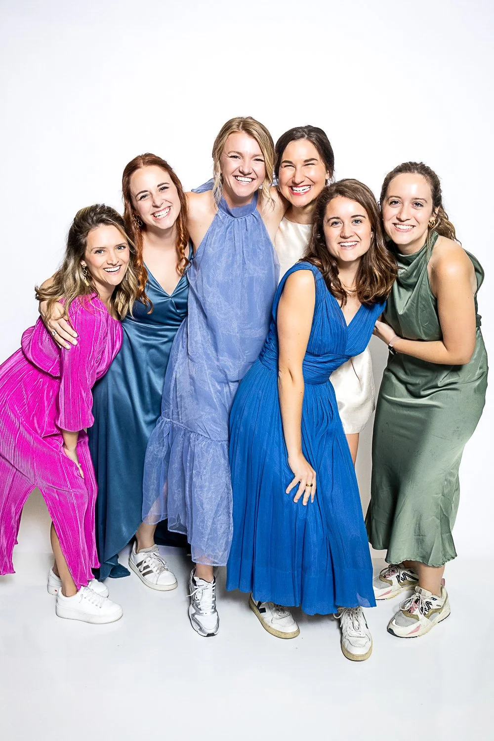 Seven women at a Memphis fundraiser gala in colorful dresses standing together, smiling in a studio with a white background.
