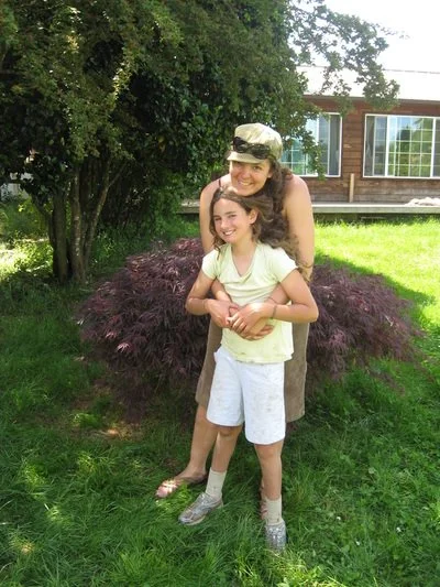 A woman in military uniform hugging a smiling girl outside in a garden.