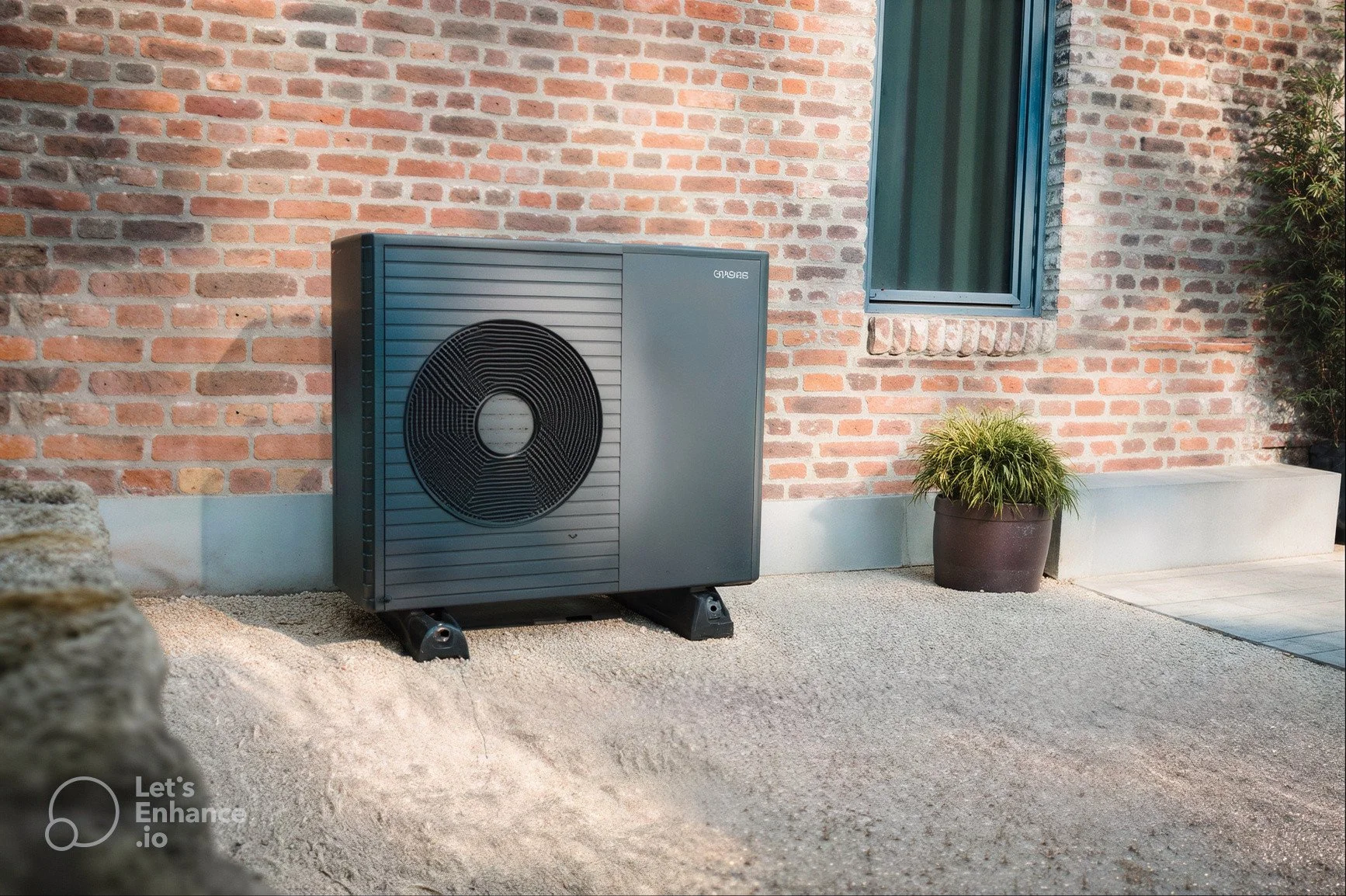 A black air source heat pump, outside by brick wall