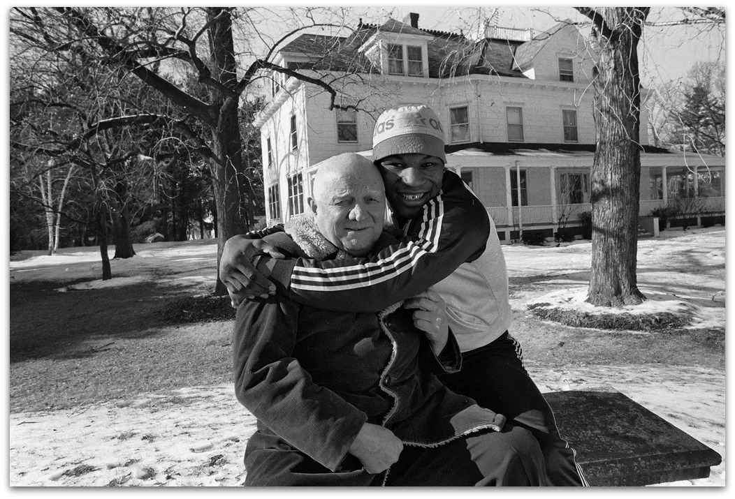 Mike Tyson smiling and hugging Cus D'Amato outside Catskills home