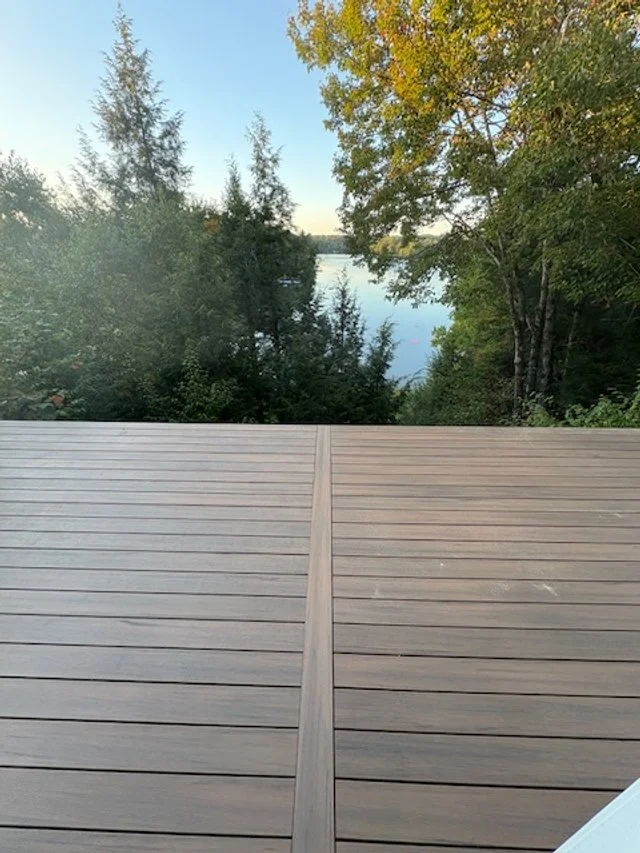 View of a lakeside surrounded by trees through a wooden deck.