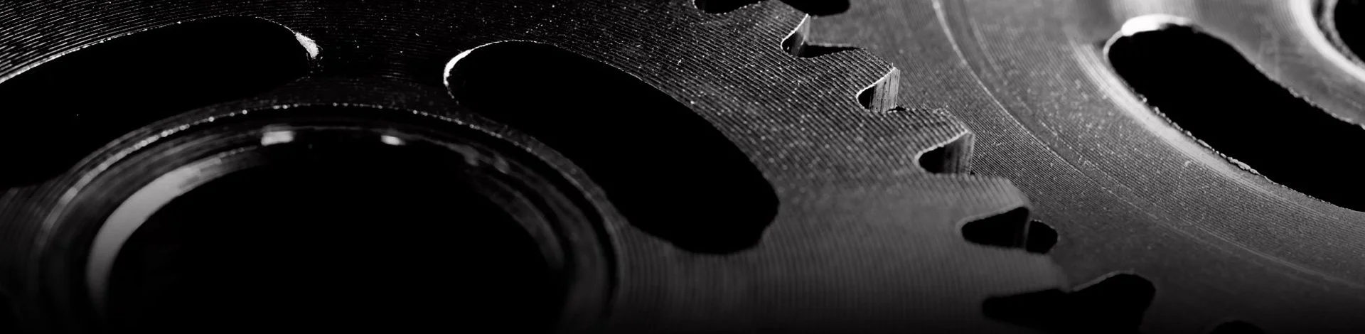 Close-up of metallic gears with teeth, in black and white.