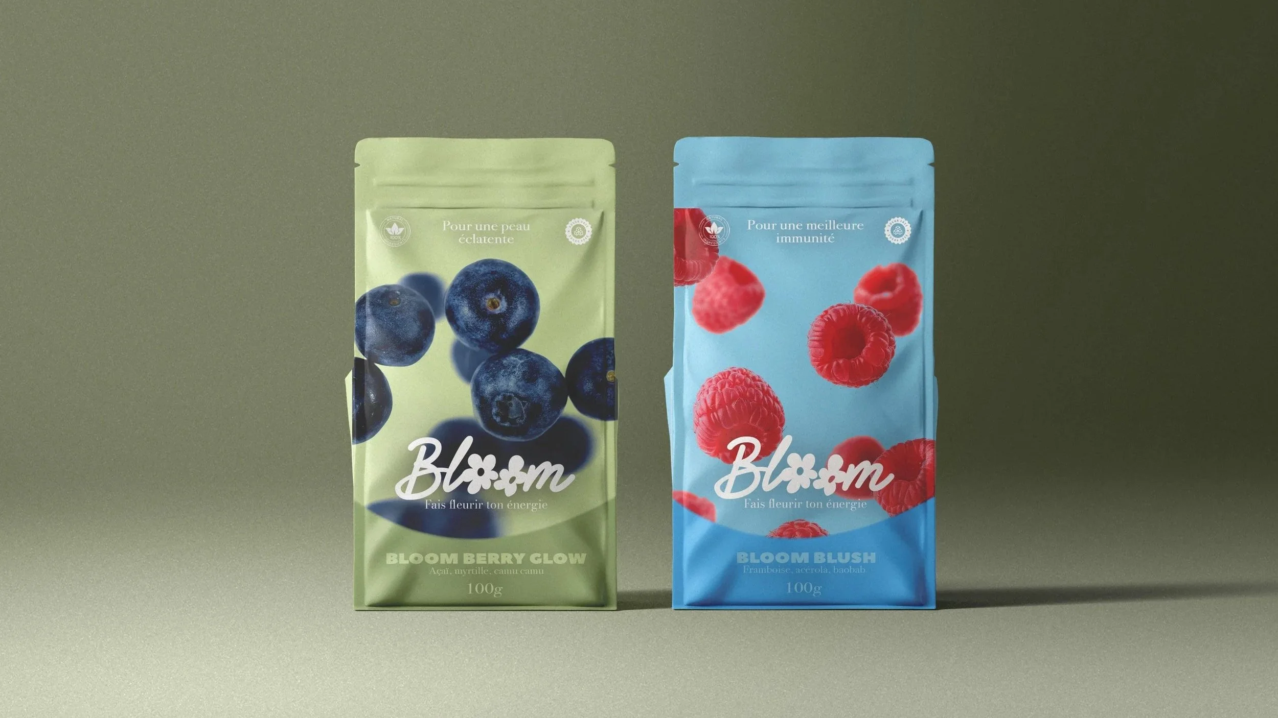 Deux paquets de poudre à boire, un à la mûre avec des myrtilles, et l'autre à la framboise, l'açai et le baobab, de la marque Bloom, sur un fond gris