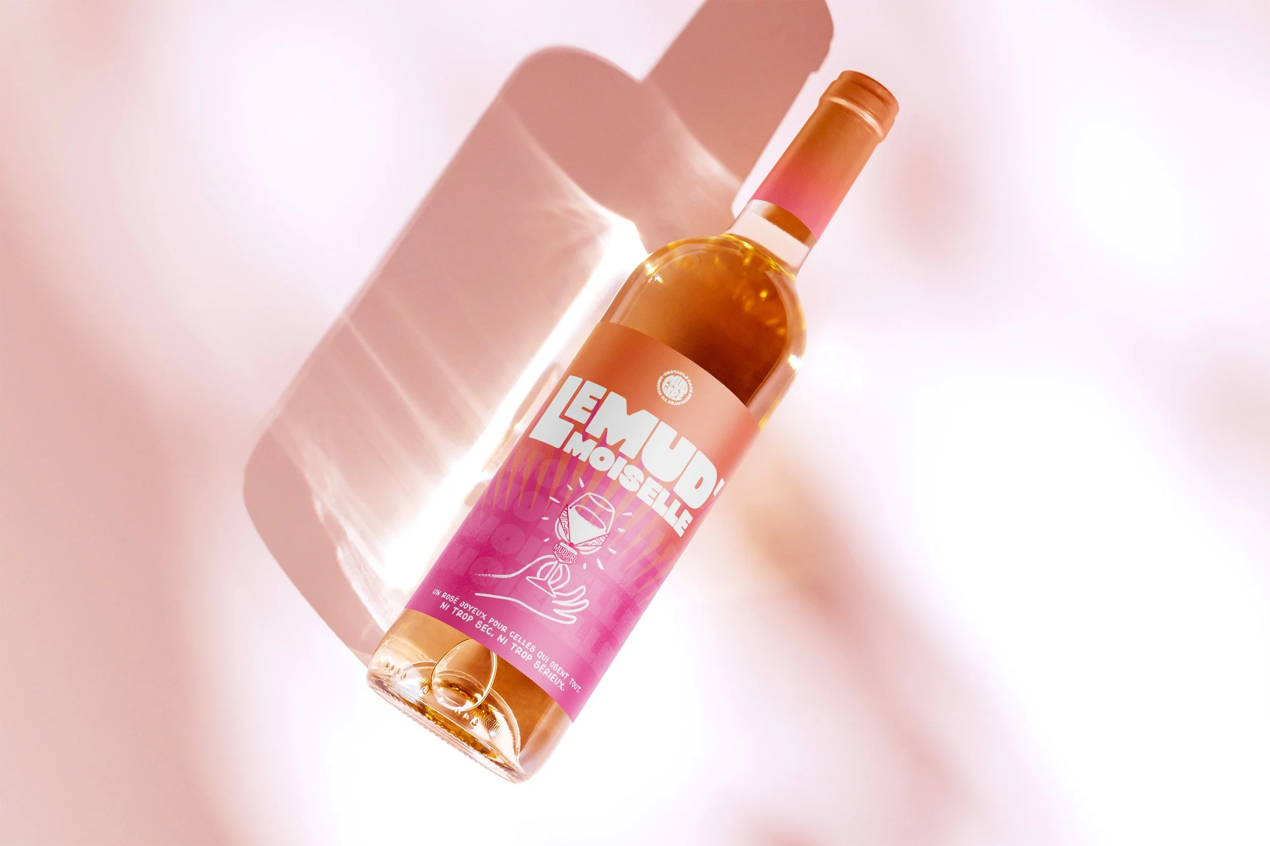 Une bouteille de vin rosé avec une étiquette rose et blanche, posée sur une surface rose, avec une lumière douce qui crée une ombre de la bouteille.」}