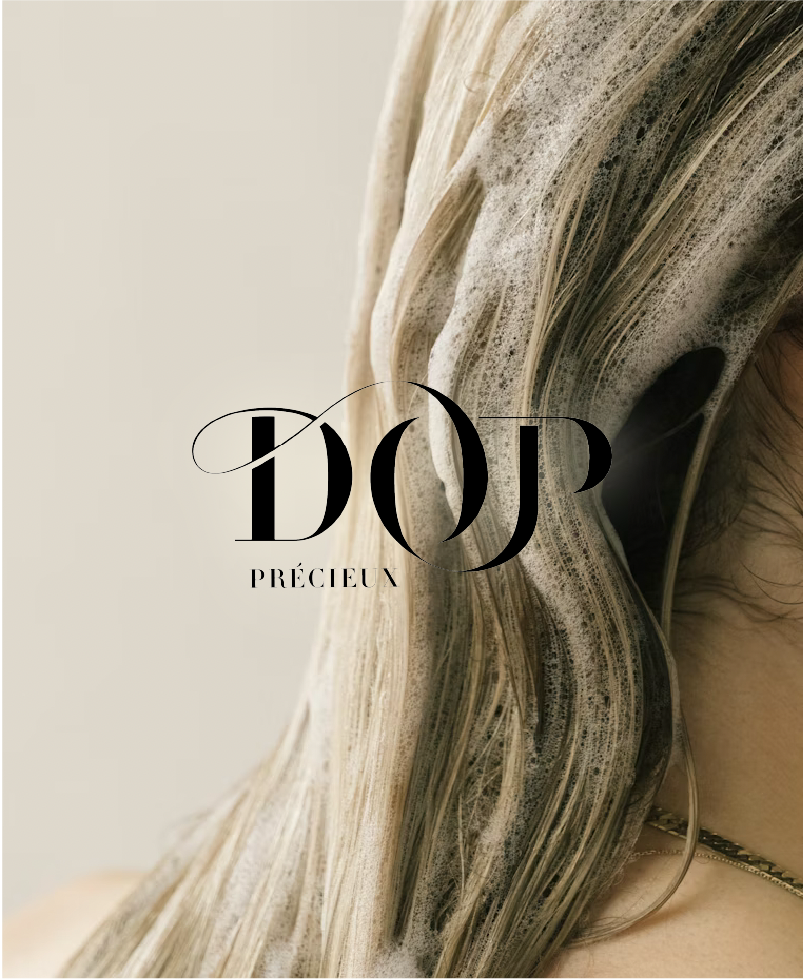 Une femme avec ses cheveux mouillés, portant un collier, vue de profil, avec un texte 'DOP PRÉCIEUX' superposé.