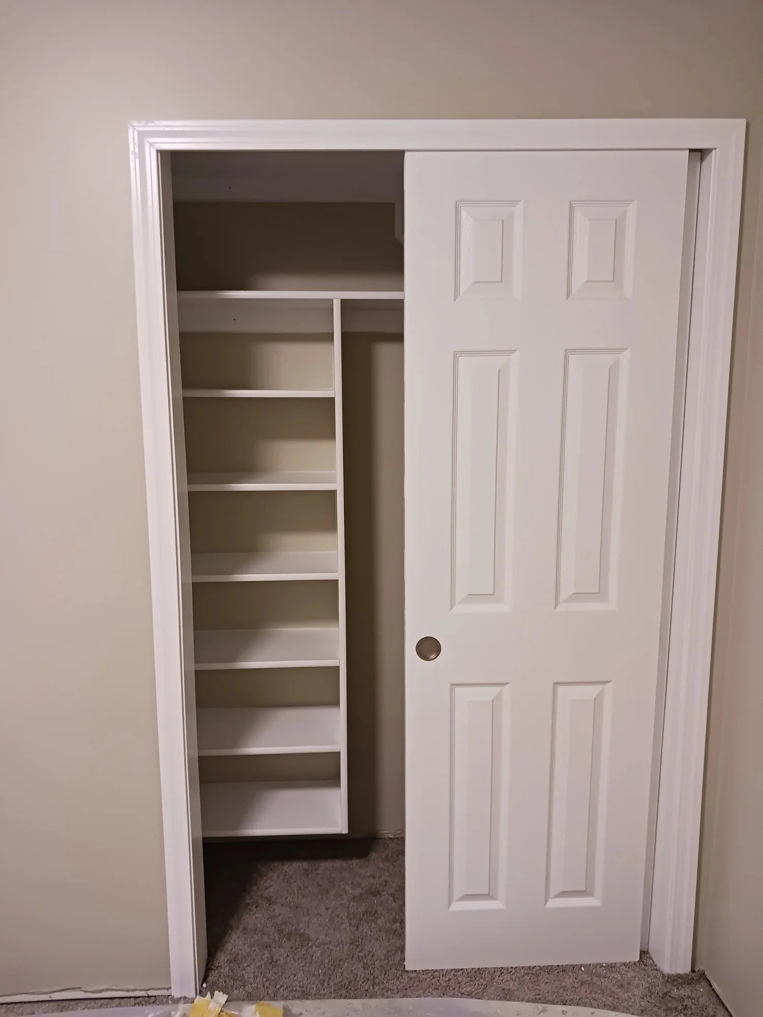 A white closet door is partially open, revealing inside shelves and a hanging rod.
