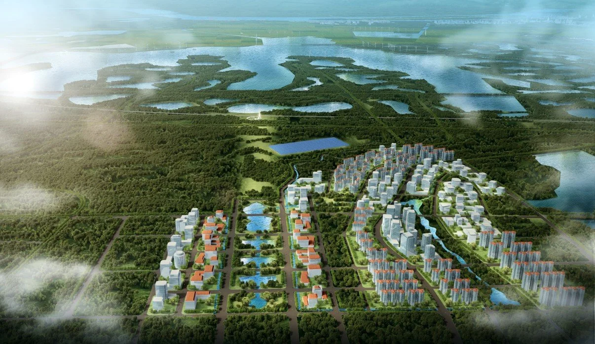 A modern residential development with apartment buildings, connected by landscaped roads and water features, surrounded by green parks and lakes.