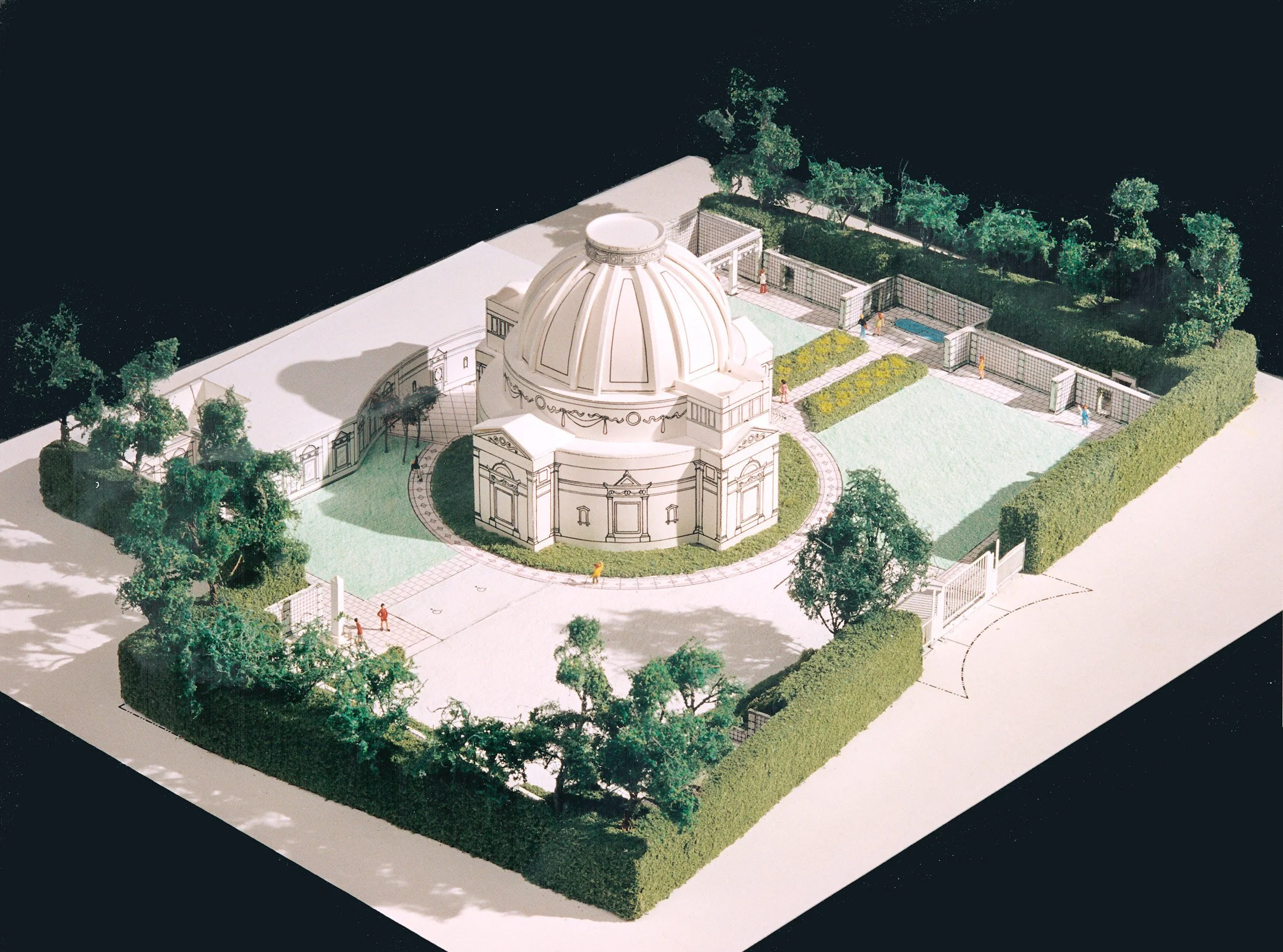 Architectural model of the Jefferson Memorial, featuring a domed structure surrounded by gardens, trees, pathways, and a fence, displayed on a white base against a black background.