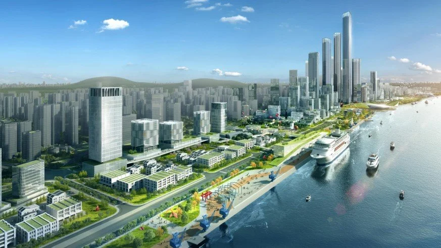 A digital rendering of a modern city skyline along a river, with high-rise buildings, a cruise ship docked at the pier, smaller boats on the water, and a waterfront park with green spaces and pathways.