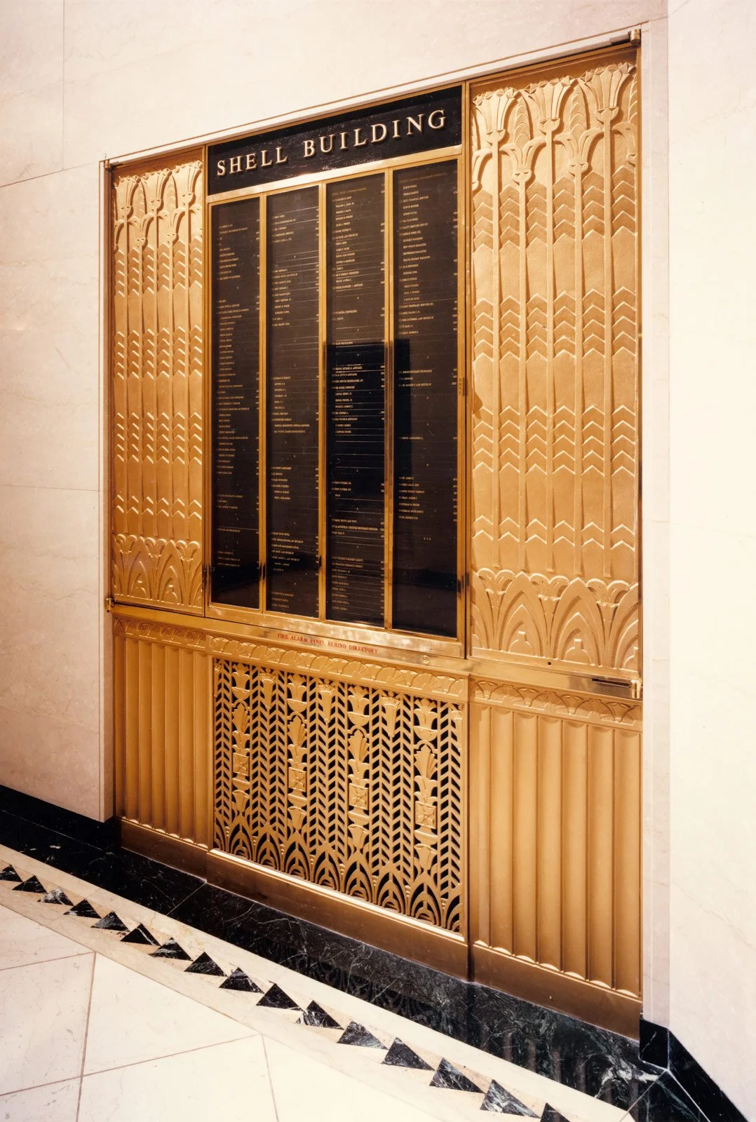 Golden Art Deco-style directory board for the Shell Building with black panels and gold lettering.