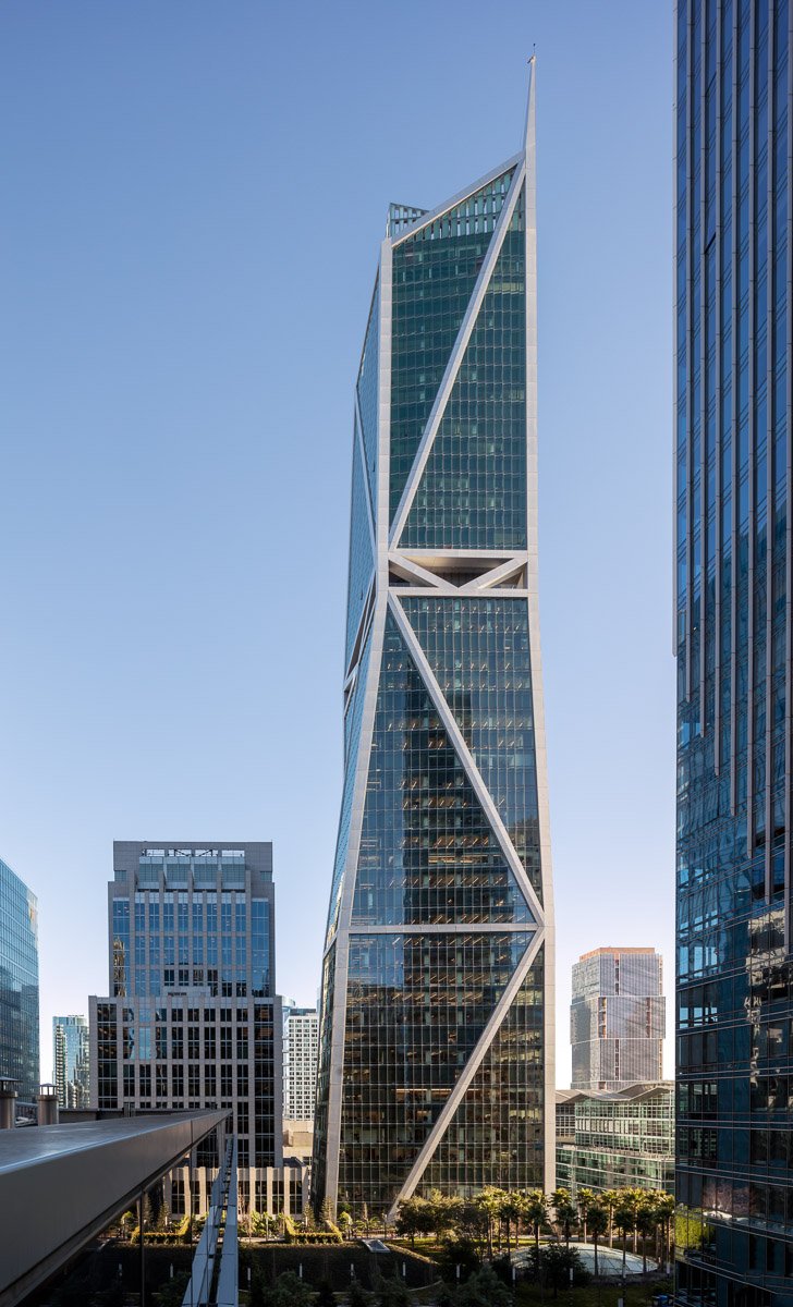 Modern skyscraper with a unique twisted design in a cityscape with other tall office buildings.