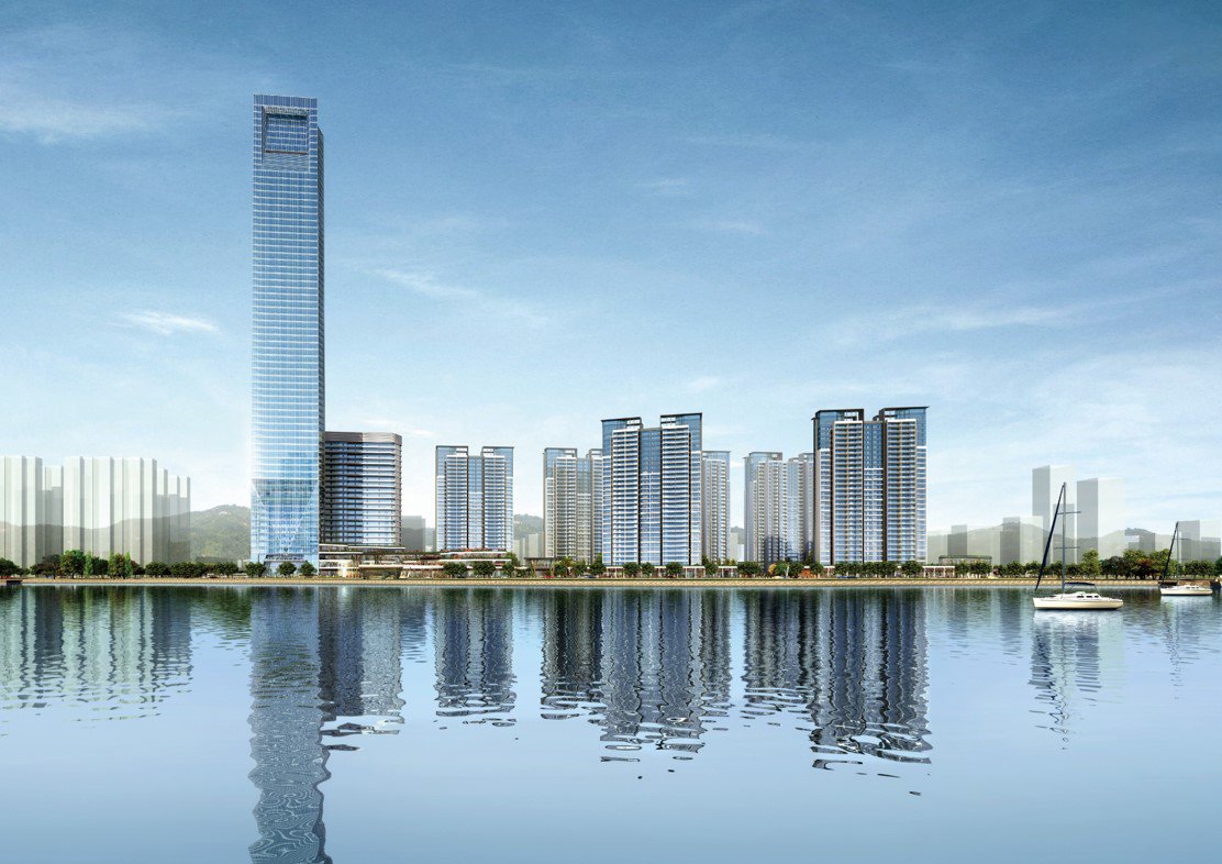 City skyline with modern high-rise buildings reflected in a body of water, including a tall skyscraper on the left and sailboats on the right.