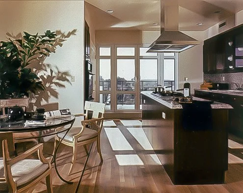 Open-concept kitchen and dining area with large windows and hardwood floors, featuring a round dining table with chairs, a kitchen island, and modern appliances.