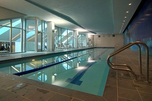 Indoor swimming pool with large windows and modern design.