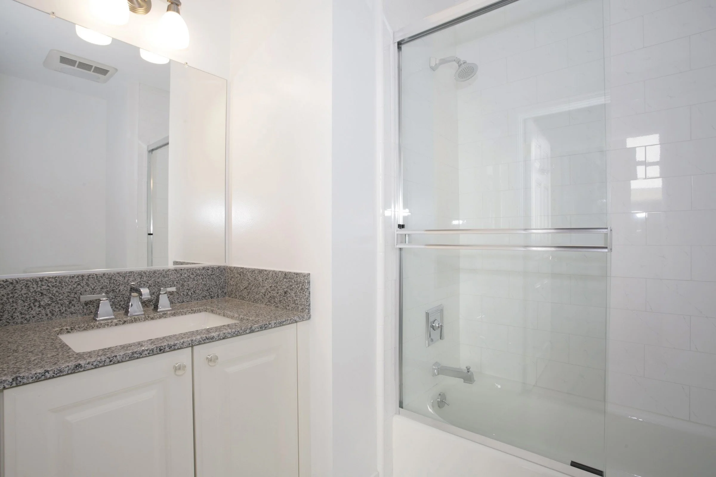 Bathroom with a granite countertop vanity and a shower with a glass door.