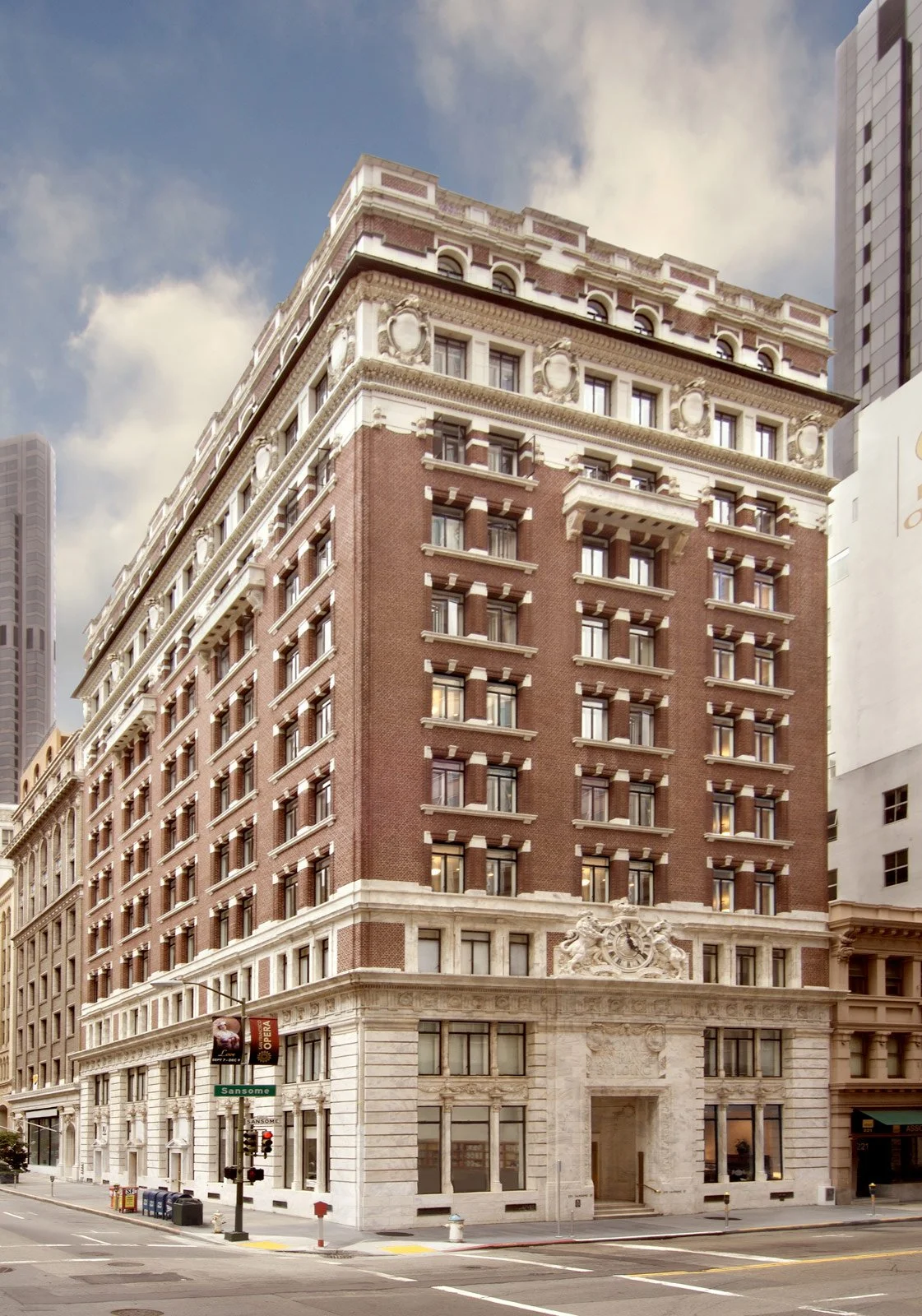 A multi-story historic building on a city street corner with brick and stone facade, decorative architectural details, and a store entrance at the ground level.