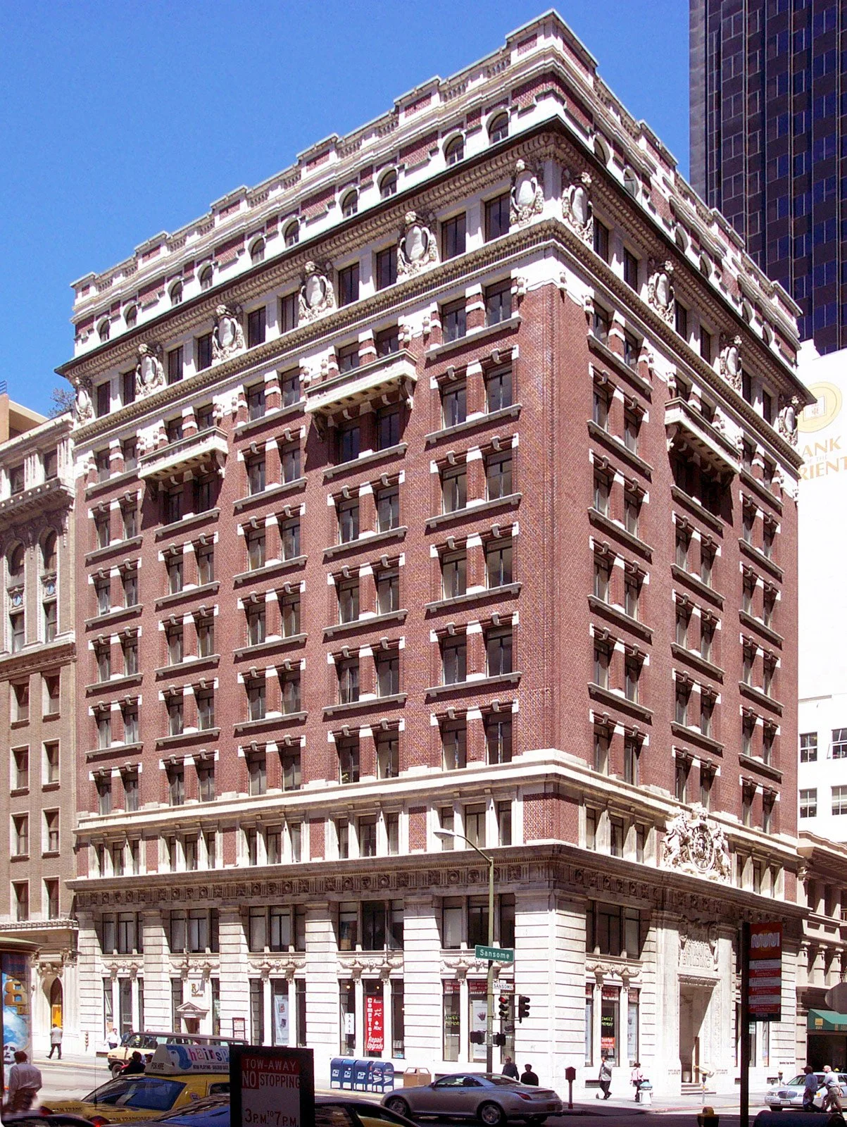 Photo of a historic multi-story brick building with ornate architectural details, situated on a busy city street corner.
